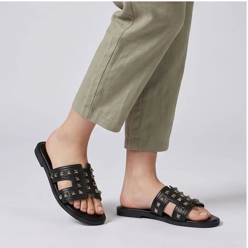 Black leather Bellamy slides with gold pyramid studs.