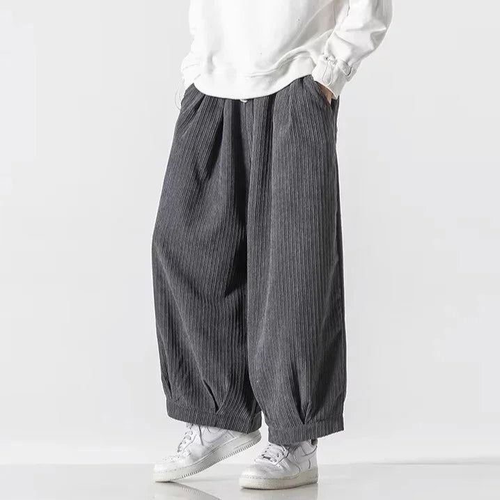 Oversized Vera corduroy pants with deep pleats and relaxed silhouette, styled with a white sweatshirt and sneakers.