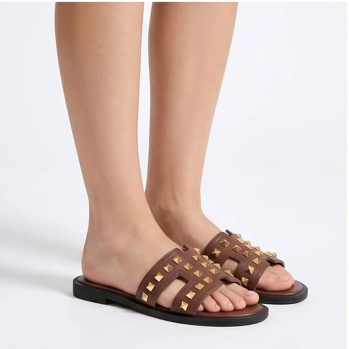 Brown leather slide sandals with gold studs.