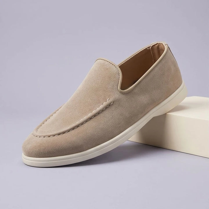 Beige suede loafers in a studio background