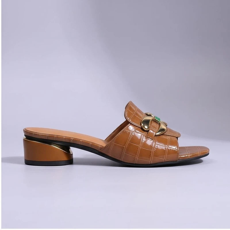 Brown crocodile-embossed leather mules with a block heel and gold buckle.