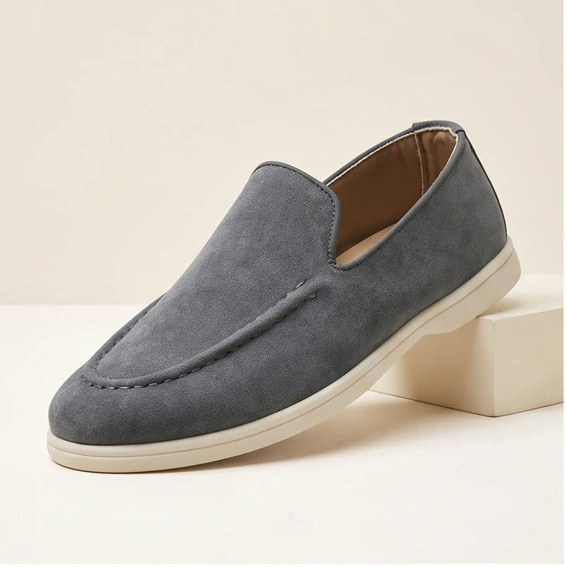 Gray suede loafers in a studio background