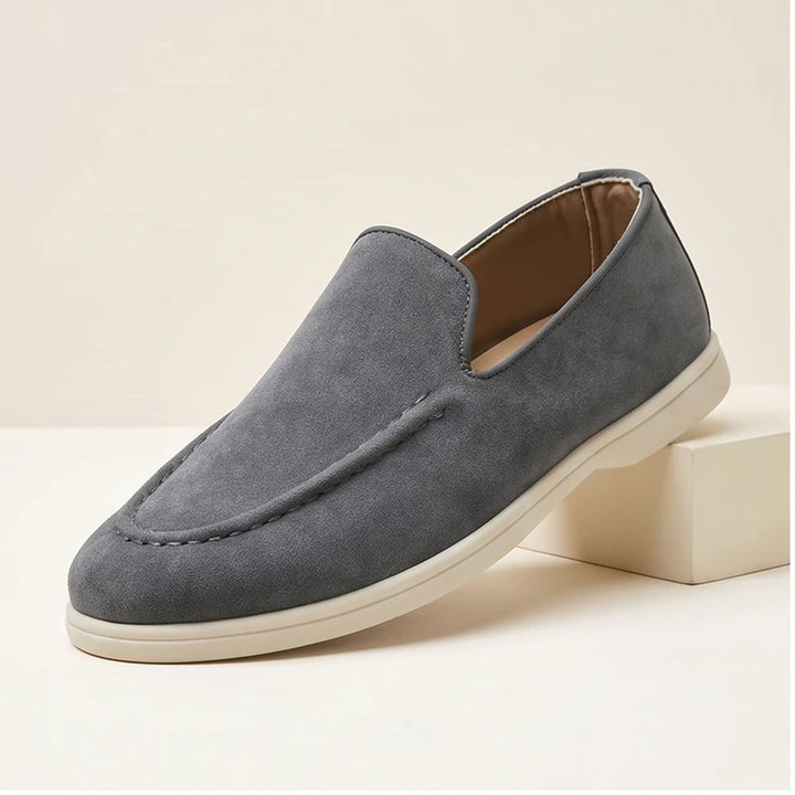 Gray suede loafers in a studio background