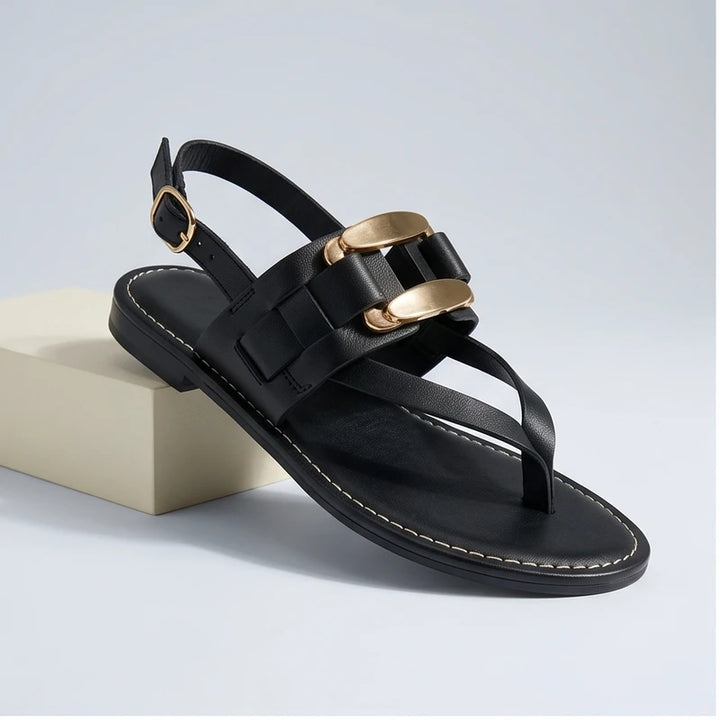 Black leather t-strap sandals with gold buckle detail and slingback.