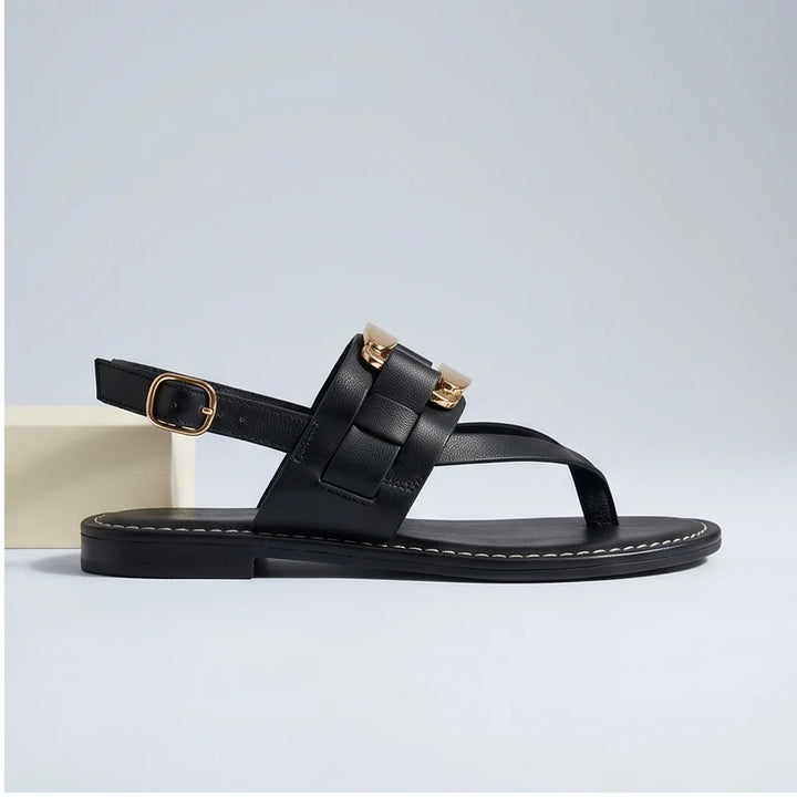 Black leather t-strap sandals with buckle and gold hardware detail.