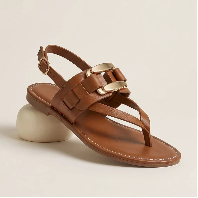 Brown leather t-strap sandals with gold buckle accent.