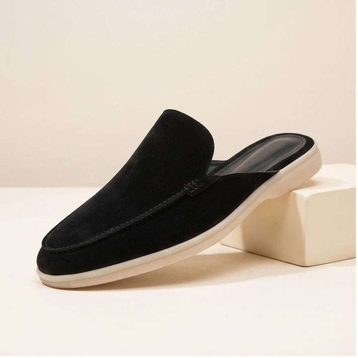 Black suede mules in a studio background