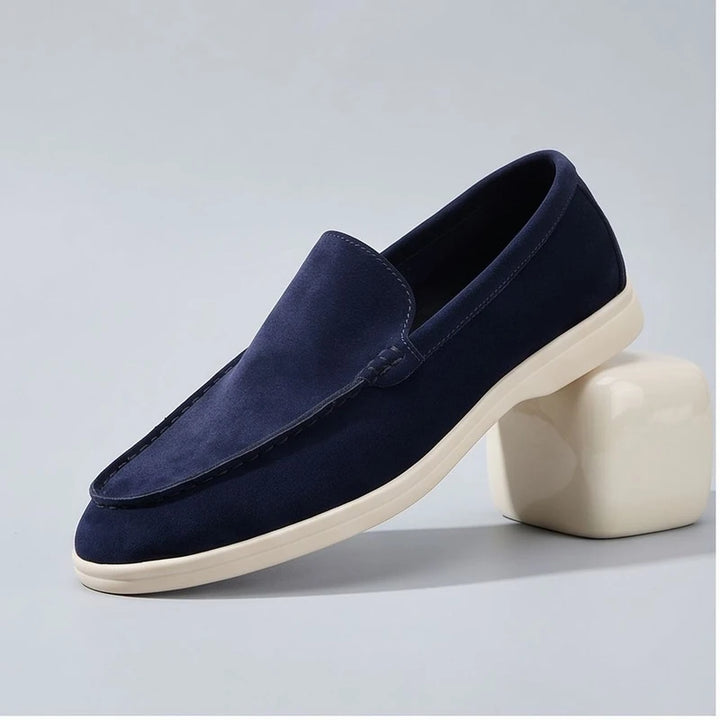 dark blue suede loafers in a studio background