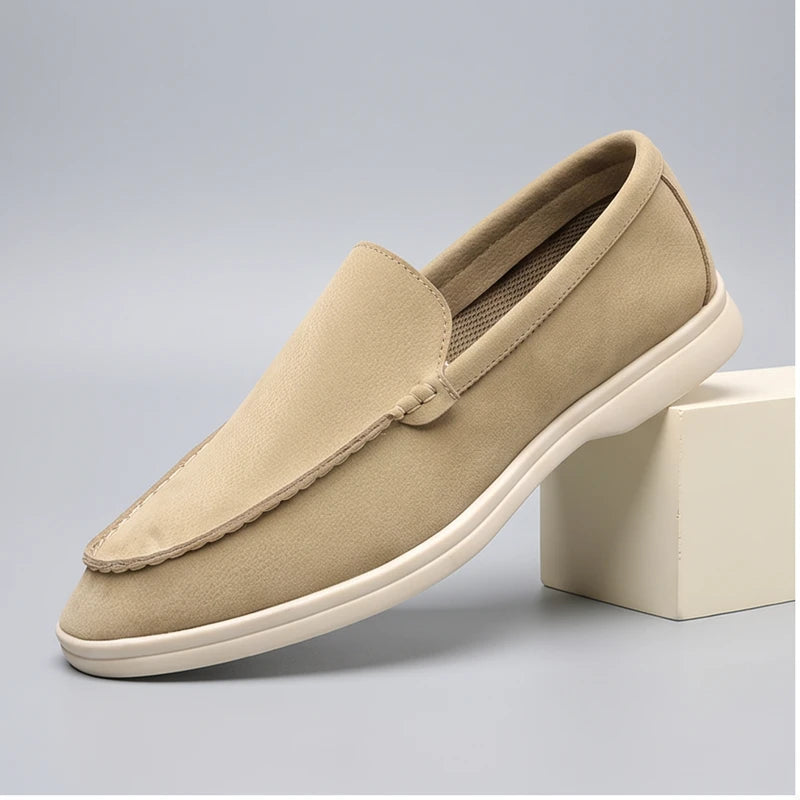 Beige suede loafers in a studio background