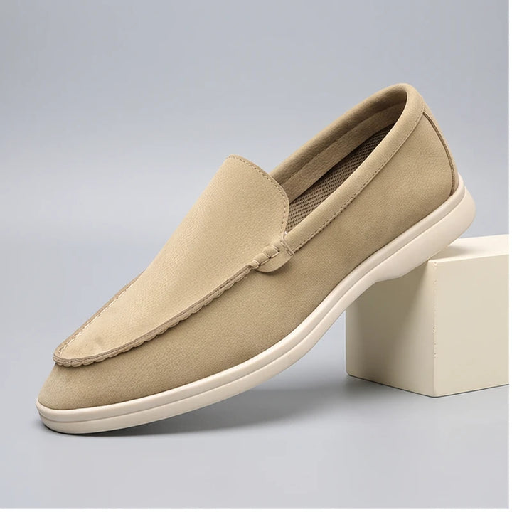 Beige suede loafers in a studio background