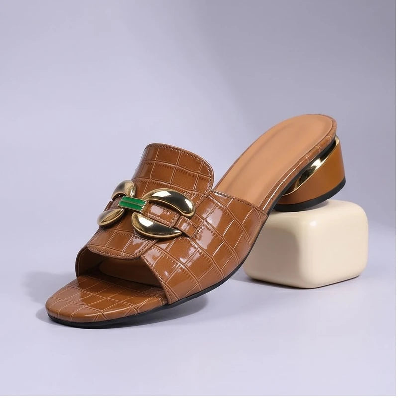 Brown crocodile embossed leather mules with gold and green accent.