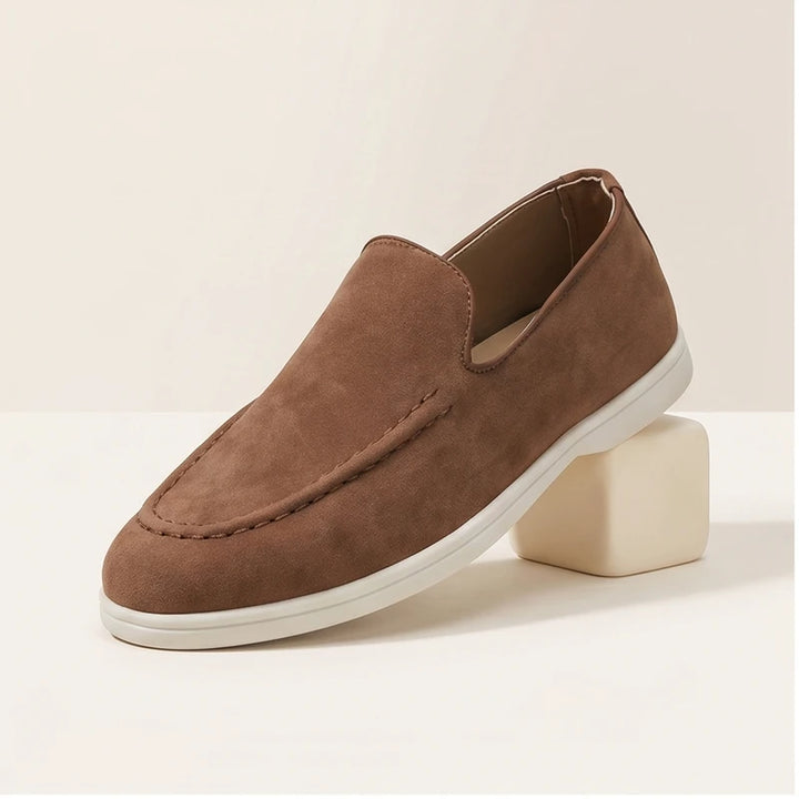 Brown suede loafers in a studio background