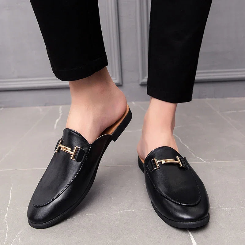 Santino Backless Slide Loafers in black with gold bit hardware, showcasing a sleek slip-on design on a person.
