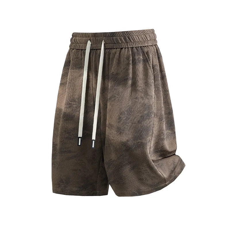 A pair of men's casual shorts in a brown and black mottled or tie-dye pattern, featuring a white drawstring. The shorts are displayed against a plain white background