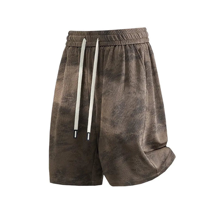 A pair of men's casual shorts in a brown and black mottled or tie-dye pattern, featuring a white drawstring. The shorts are displayed against a plain white background