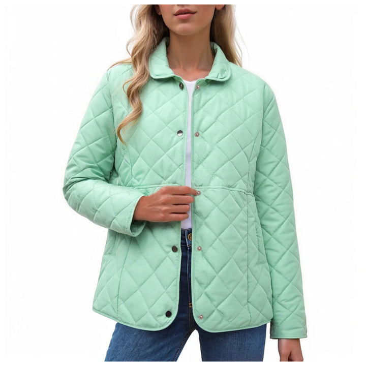 Woman wearing an unbuttoned light green quilted jacket with a pointed collar, shown over a white top and blue jeans.