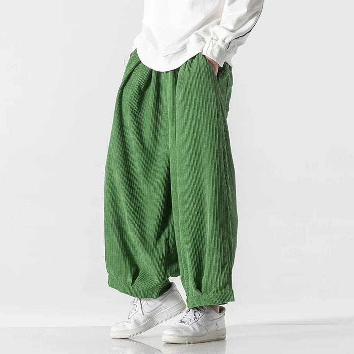 Oversized green corduroy pants with deep pleats, elastic waistband, and wide-leg silhouette for effortless comfort.