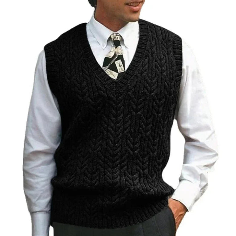Man wearing a black knitted vest over a white shirt with a patterned tie on a white background