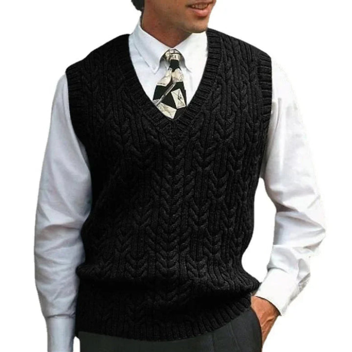 Man wearing a black knitted vest over a white shirt with a patterned tie on a white background