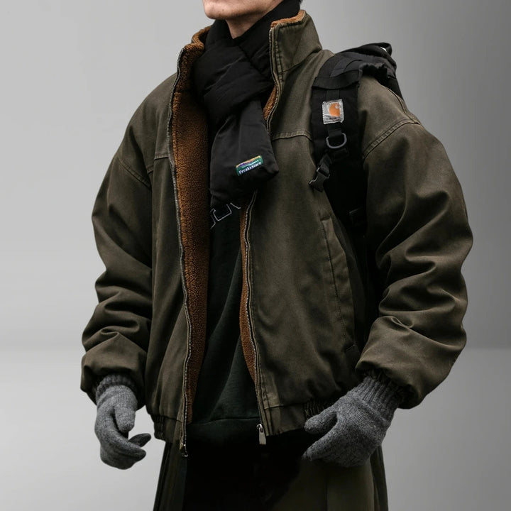 Man wearing a dark olive canvas zip-up jacket with fleece lining, styled with a black scarf and grey knit gloves.