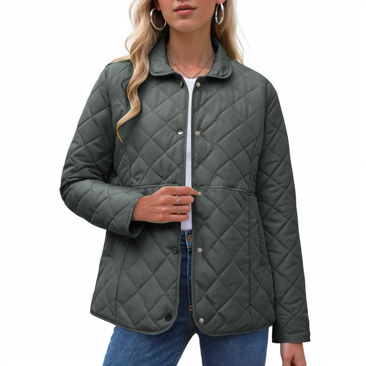 Woman wearing a dark gray quilted jacket with a collared neckline and silver snap buttons, over a white top and blue jeans.