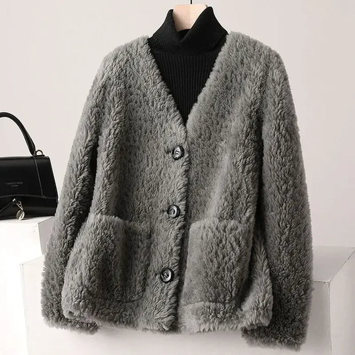 Gray fluffy cardigan on a mannequin with a black handbag in the background