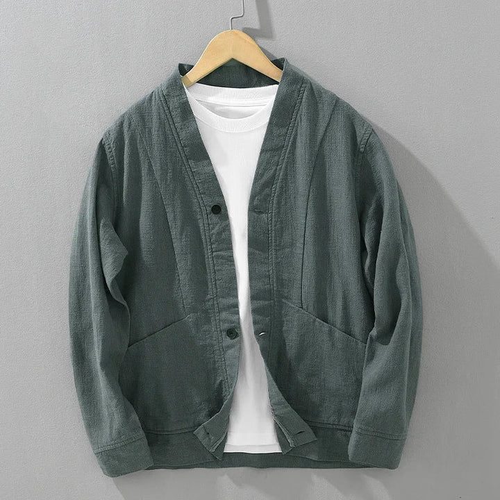 Green linen jacket over a white shirt on a hanger against a gray background
