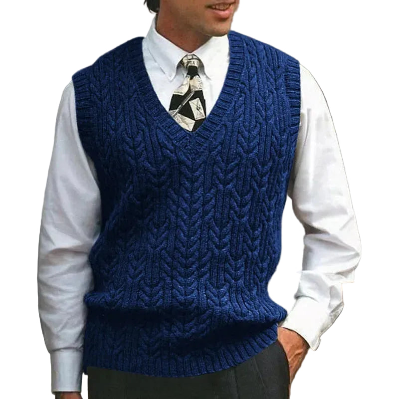 Man wearing a blue knitted vest over a white shirt with a patterned tie.