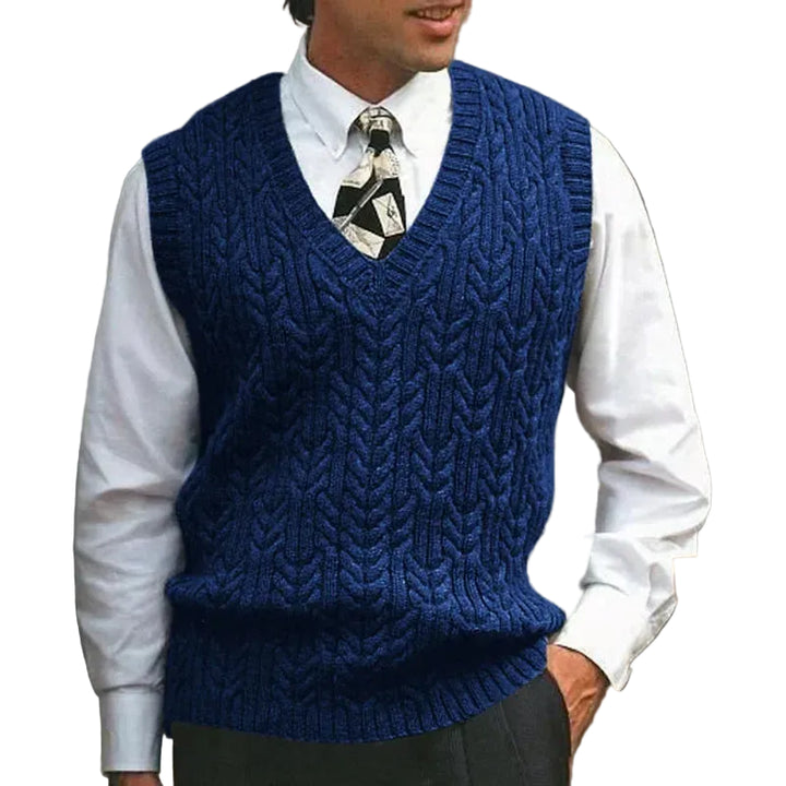 Man wearing a blue knitted vest over a white shirt with a patterned tie.