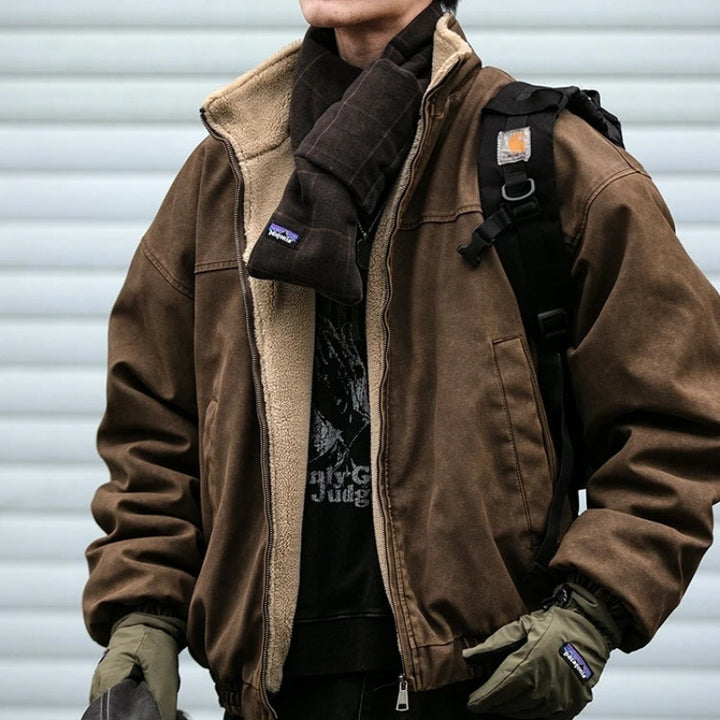 Man wearing an open brown canvas work jacket with beige sherpa lining, styled with a dark fleece scarf.