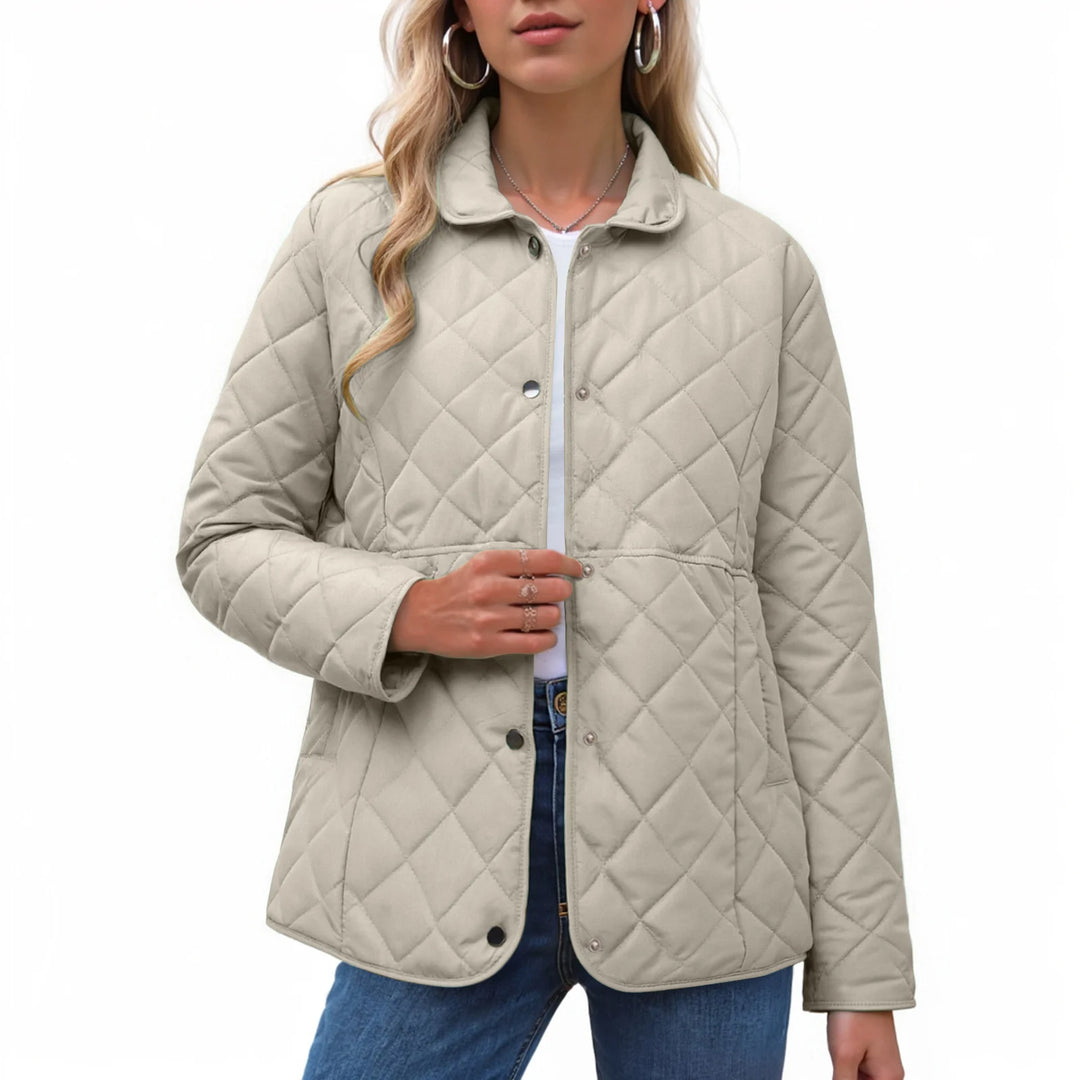 Woman wearing a light beige diamond-quilted jacket with a collar and snap buttons over a white shirt and blue jeans.