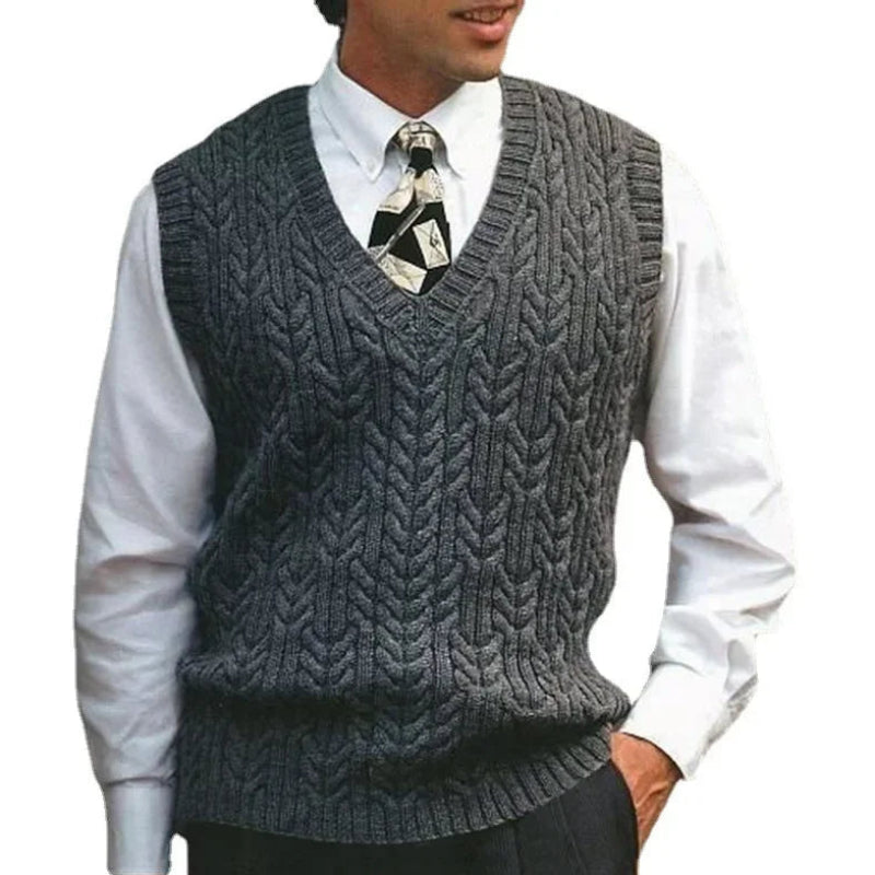 Man wearing a gray knitted vest over a white shirt with a tie on a white background