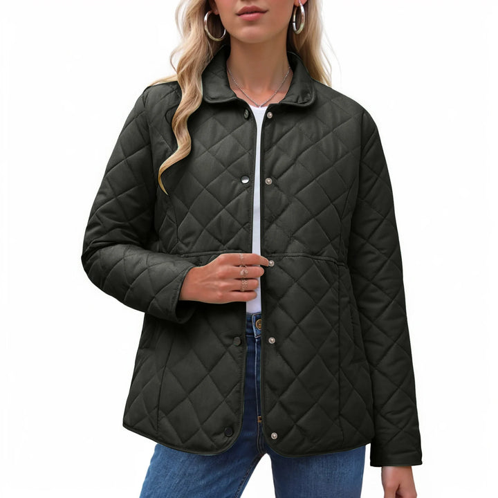 Woman wearing a dark gray quilted jacket with a collared neckline and silver snap buttons over a white shirt and jeans.