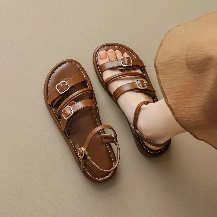Luna Leather Flat Sandals in brown, featuring soft straps, cushioned footbed, and triple buckle closures for a secure fit.