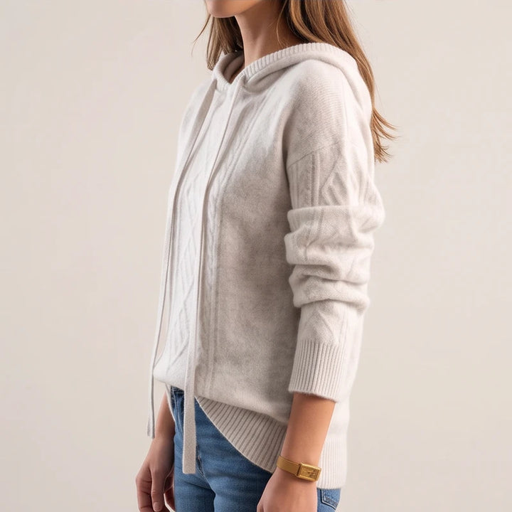 Woman model wearing cream knit sweater in a studio from a side profile