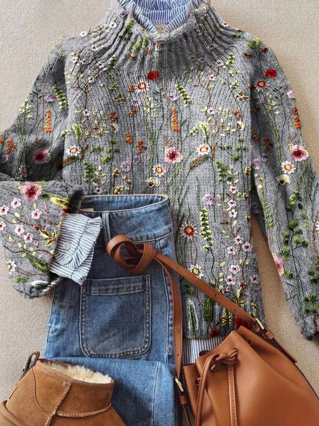 Embroidered sweater with floral patterns, blue jeans, brown boots, and a brown leather bag on a neutral background.