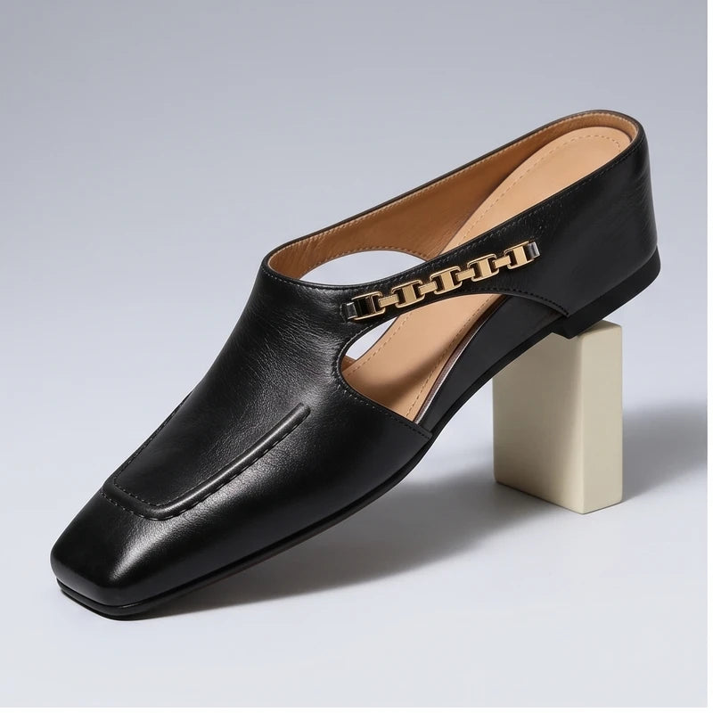Black leather square-toe mules with gold chain detail.