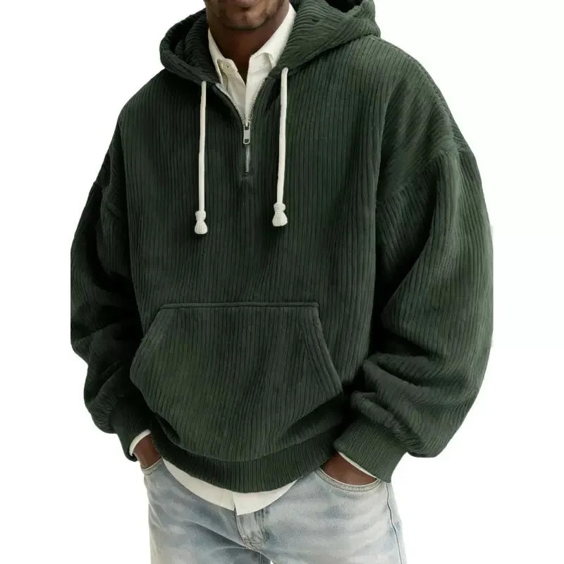 Man wearing a dark green corduroy half-zip hoodie with white drawstrings and a front kangaroo pocket.