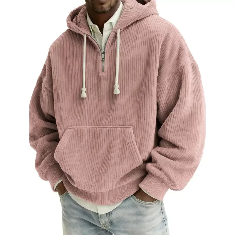 Man wearing a loose-fit pink corduroy hoodie with a half-zip closure, front pouch pocket, and white drawstrings.