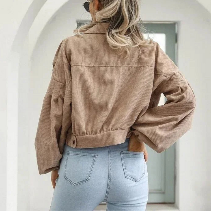 Woman with blonde hair, back to camera, wearing a loose-fit, light brown cropped corduroy jacket with light blue jeans.