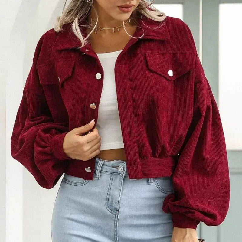 Woman wearing a dark red corduroy jacket with large sleeves, chest pockets, and silver snap buttons over a white top.