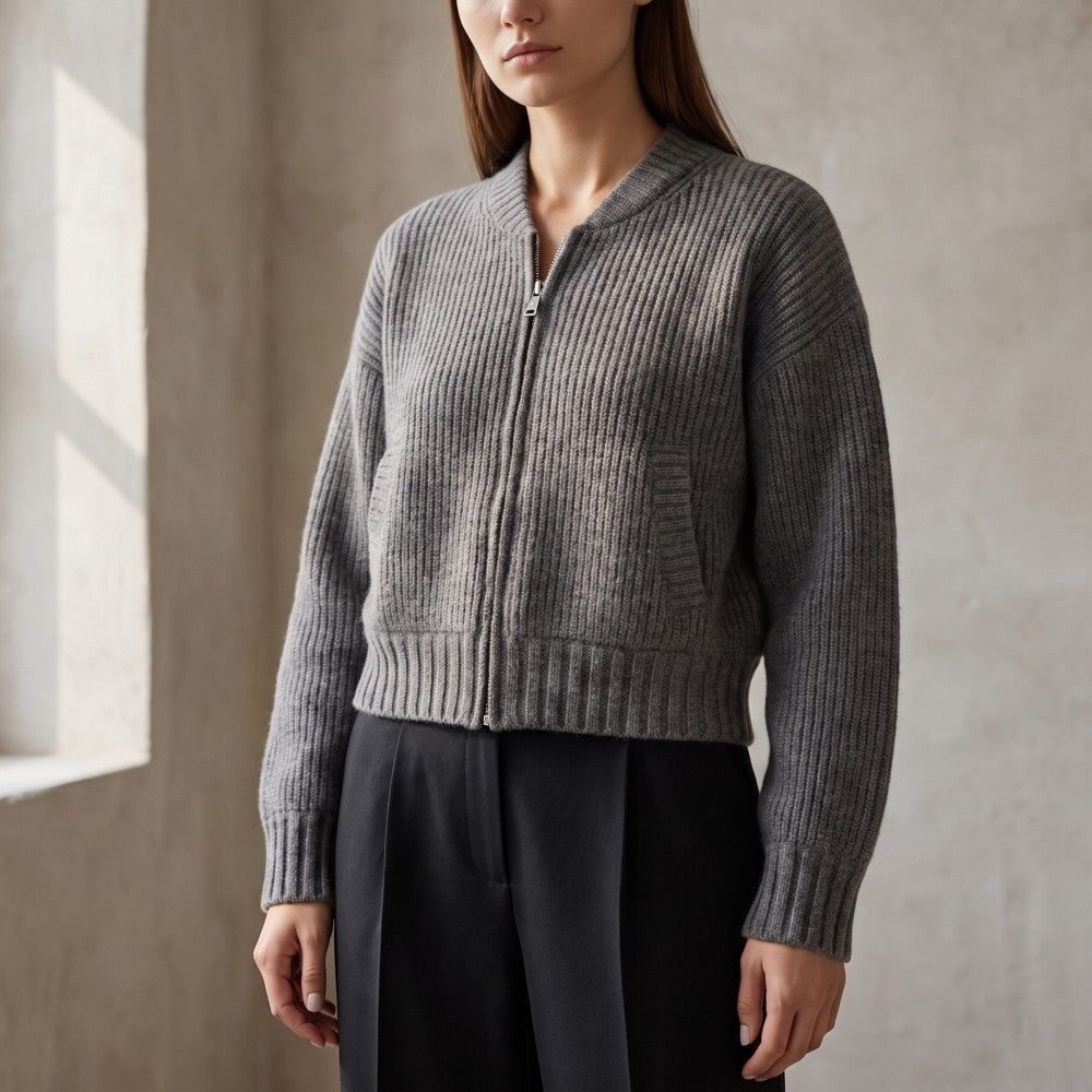 Woman wearing a charcoal gray ribbed knit cardigan with a silver zipper, black trousers, in an indoor setting.
