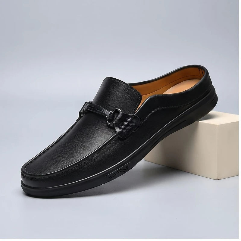 Black leather mules in a studio background