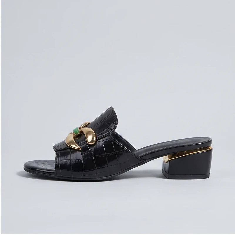 Black crocodile embossed block heel mules with gold hardware.
