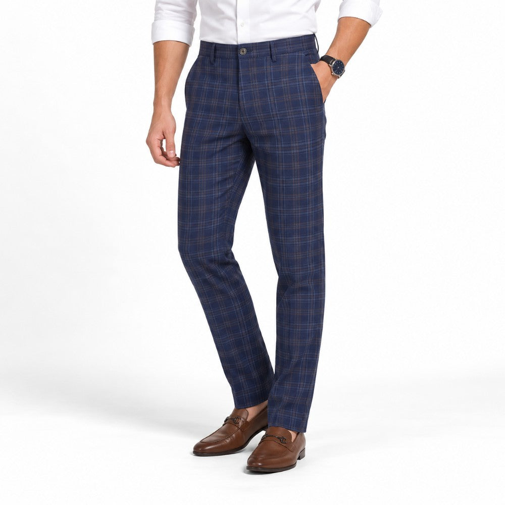 Man wearing blue and brown plaid dress slacks with a white shirt and brown leather loafers on a white background.