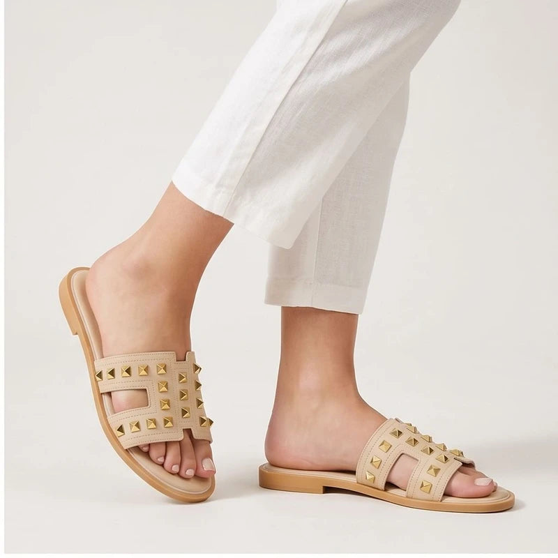 Beige leather slides with gold studs.