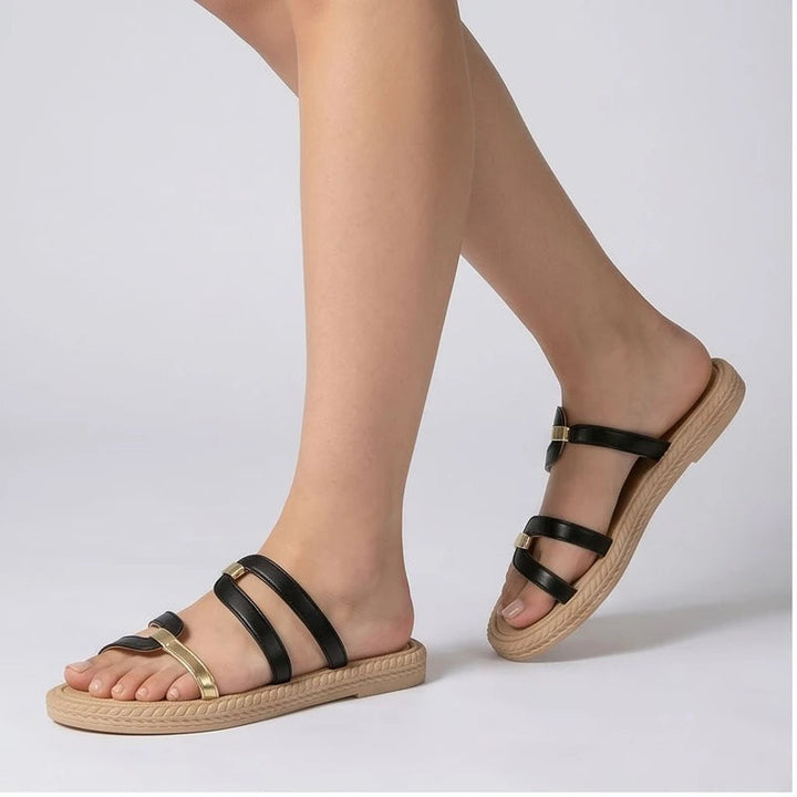 Black and gold leather slide sandals with tan soles.