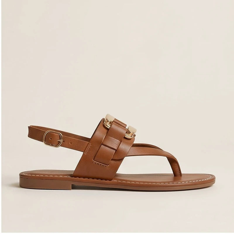 Brown leather t-strap sandals with gold hardware and buckle strap.