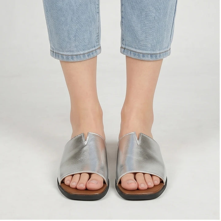 Model wearing Silver Shiny Metallic Flat Slides for Women Square Toe Open Toe Lightweight Comfortable Summer Beach Casual Daily Walking Shoes in studio