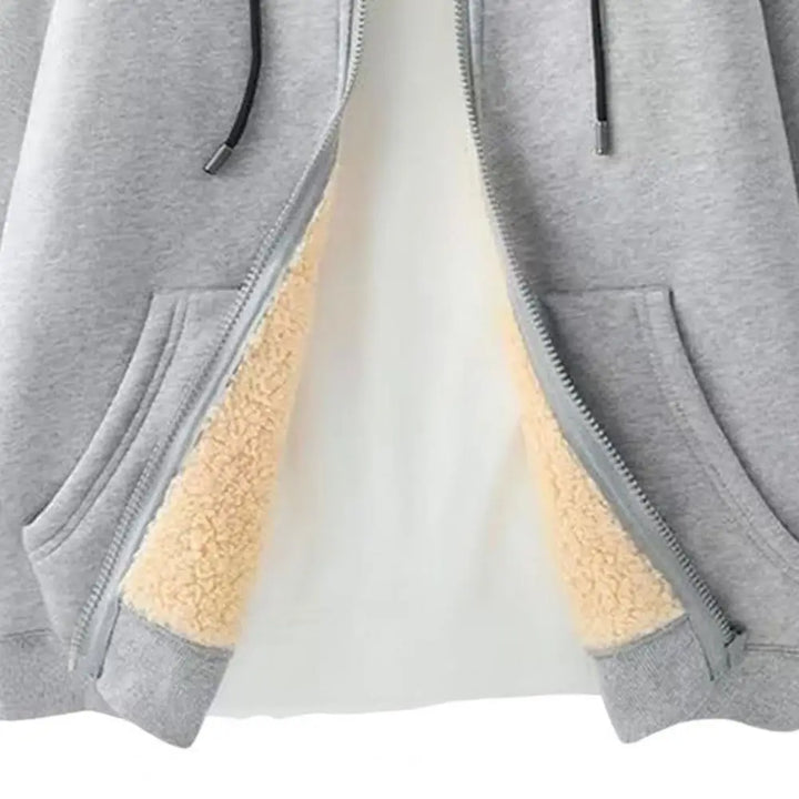 Close-up of a partially unzipped grey hoodie revealing its soft, cream-colored fleece lining and front pockets.
